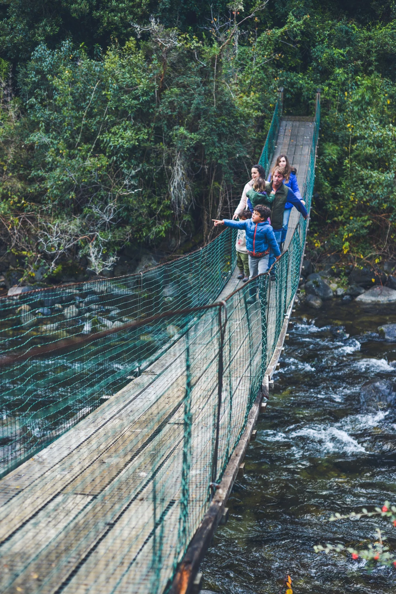 Familia cruzando el puente colgante sobre el río Liucura